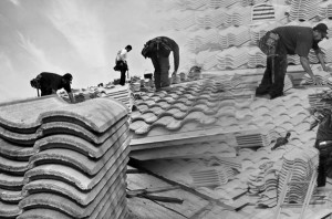 Multiple men working on different types of roofs